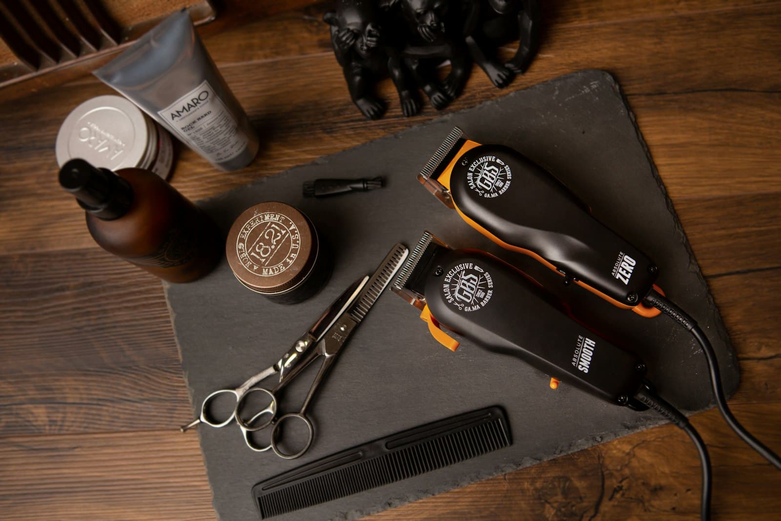 Two clippers, shears and a comb on slate.